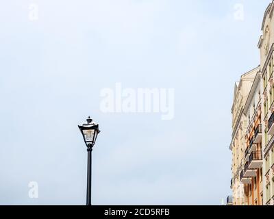 Street lamp against the background of a cloudy sky and a fragment of a building Stock Photo
