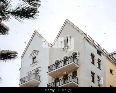 Top of a white building with a double triangular roof against the sky during a snowfall Stock Photo