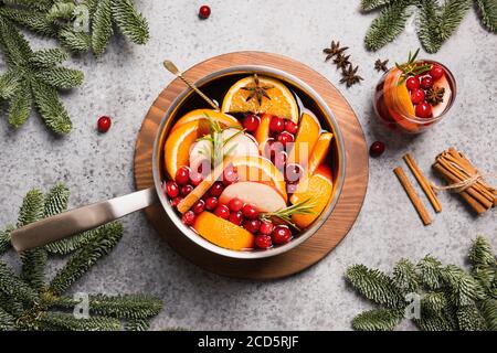 Mulled wine with cinnamon, cranberry, orange in ladle and glass on grey table. Stock Photo