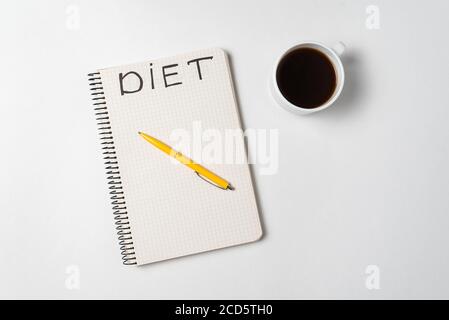 Cup of coffee, pen and a notebook title Diet. White background directly above Stock Photo