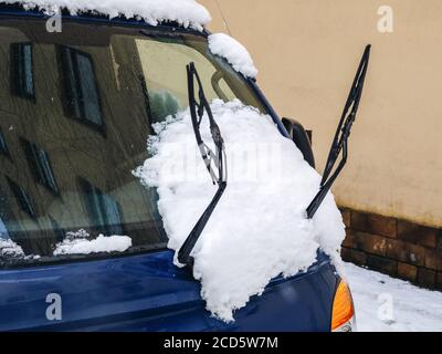 Fragment of a blue car with raised wipers and snow on the windshield Stock Photo