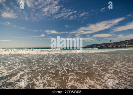 Guincho beach sea with surfers doing kitesurf and with the blue sky in the background, Cascais, Portugal Stock Photo