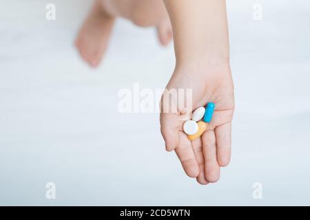 child hand with colorful pills on white background top view. Vitamins for children. Stock Photo