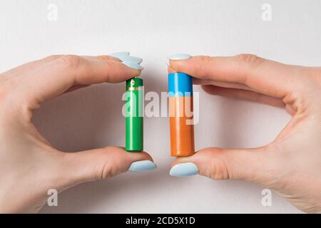 Two generic AA and AAA batteries in hands. Generic accumulators on white background. Stock Photo