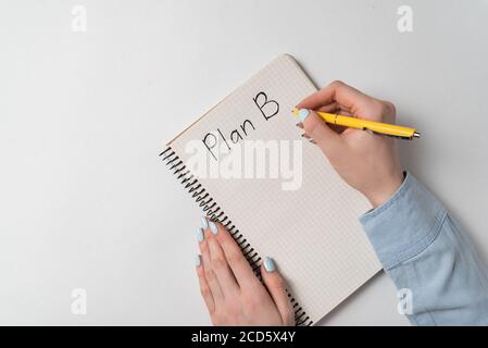 Top view of the notepad with Plan B notice on white background. Woman writes in copybook. Stock Photo