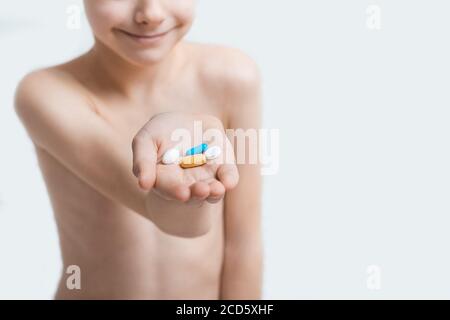 Boy child holds tablet in hands on white background. Vitamins for children. Stock Photo