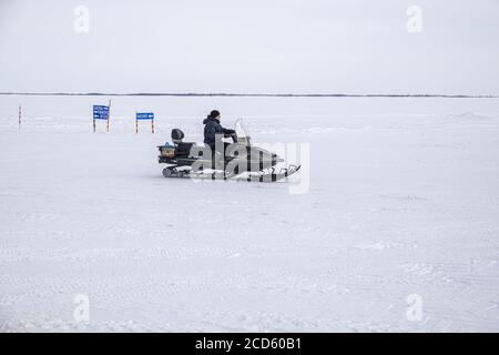 A Nenet man driving a snowmobile on the frozen waters of Ob River, Yamalo-Nenets Autonomous Okrug, Russia Stock Photo