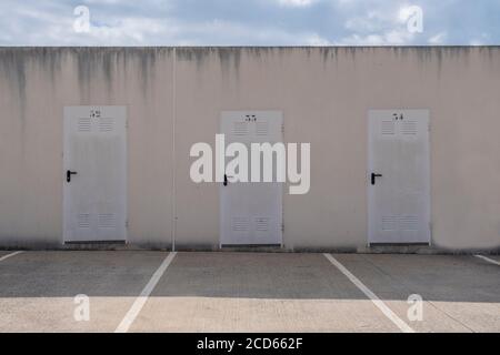 Three storage room doors against a blue sky. Simmetry in a minimalist background. Epmty copy space for Editor's content. Stock Photo