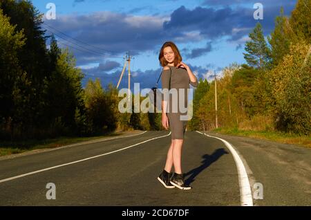 a woman in a gray dress is walking along the road Stock Photo
