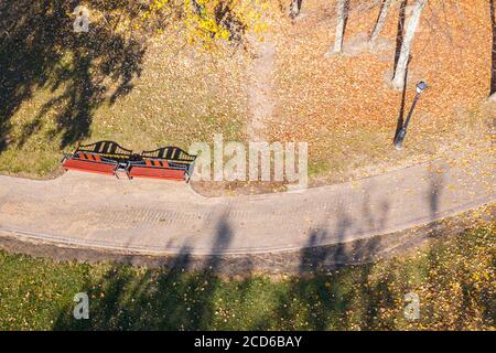 park walkway with empty benches and fallen leaves in autumn sunny day. top view aerial photo Stock Photo