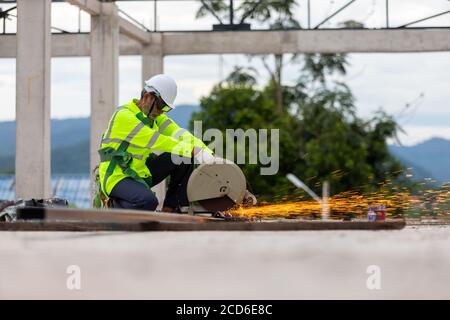 Asian senior worker cutting steel on the roof truss construction site Stock Photo