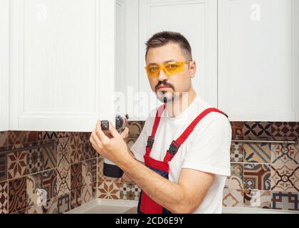 Maintenance worker installing new furniture with screwdriver and look at camera Stock Photo