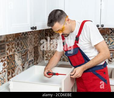 Man worker assembling new furniture in kitchen Stock Photo