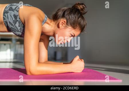 Home fitness, workout at home girl training indoors floor exercises on exercise mat in apartment condo. Asian woman planking doing bodyweight yoga Stock Photo
