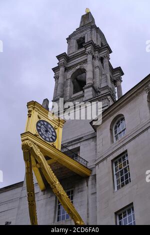 LEEDS, UNITED KINGDOM - Jul 15, 2020: Vertical Image of Leeds Civic Hall to the right of a bright golden clock on a clound dull day Stock Photo