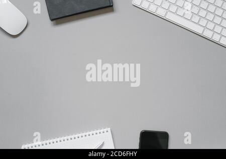 Workplace of an office worker or freelancer keyboard, mouse, gliders and diaries, ballpoint pen, phone on a gray background with copy space. Stock Photo