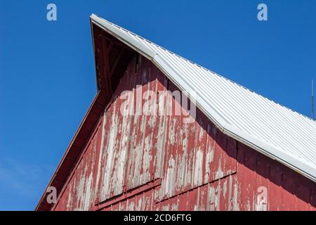 Close upward view of a hayloft door on a rustic late 19th Century wooden barn with blue sky and copy space Stock Photo