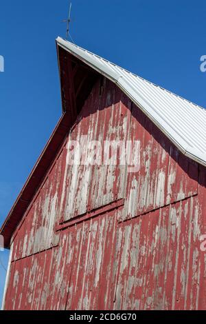 Close upward view of a hayloft door on a rustic late 19th Century wooden barn with blue sky and copy space Stock Photo