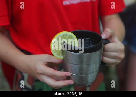 Children's hands hold a red mug with tea in the autumn park Stock Photo