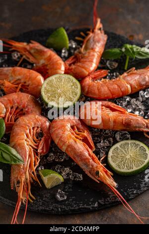 Prawns or shrimps with lemon in ice on slate board Stock Photo