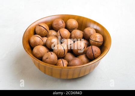 natural organic macadamia nuts in wooden bowl on gray concrete background Flat lay Top view Healthy snack Nuts with essential oil rich in vitamins B Stock Photo