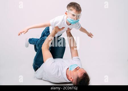 Father and son play during quarantine in medical masks. Stock Photo