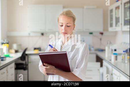 Portrait of young, confident female health care professional taking notes during inventory in scientific laboratory or medical doctors office Stock Photo