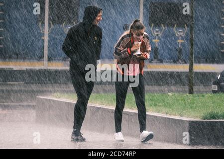 UK Weather: Young women wearing a face mask and Young Man caught in a heavy rain shower, Preston, UK Stock Photo