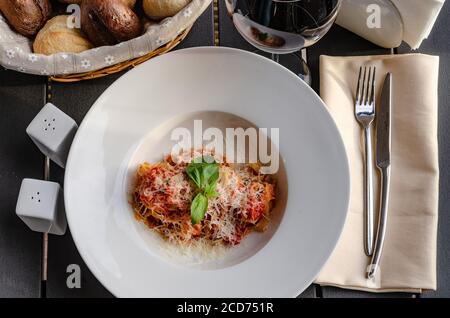 Italian pasta with tomatoes, cheese and a sprig of basil Stock Photo