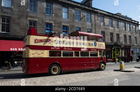 Tourists enjoying an open top bus tour of the city of Edinburgh on a vintage double decker bus. Stock Photo