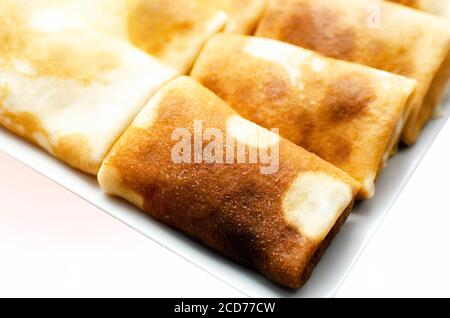 Pancakes stuffed on a plate with sour cream isolated on white background Stock Photo
