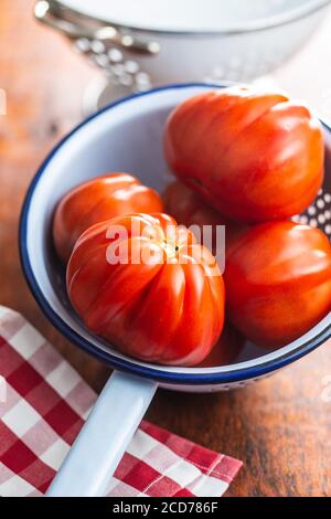 Red beefsteak tomatoes in colander. Stock Photo