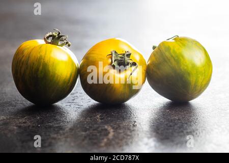 Green zebra tomatoes on black table. Stock Photo