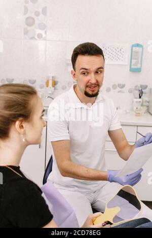 Dentist shows an x-ray of the patient's teeth to a cute woman. Reception at the dentist. Stock Photo