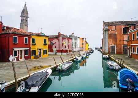 Beautiful canal in Burano with the typical colorful houses and the leaning campanile (bell tower) of San Martino Church.