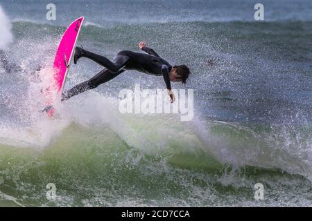 Spectacular action as a male surfer rides a wave at Fistral in Newquay in Cornwall. Stock Photo