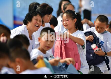 (200827) -- LANZHOU, Aug. 27, 2020 (Xinhua) -- Children receive schoolbags and stationery donated by the China Construction Third Engineering Bureau Co., Ltd. during a caring activity in Anning District of Lanzhou, northwest China's Gansu Province, Aug. 27, 2020. A caring activity for left-behind children in rural areas was held at a construction site of a women and children's hospital in Lanzhou on Thursday. Experts and volunteers conducted safety knowledge education to children and communicated with parents who are migrant workers here on family education and communication between parents a Stock Photo