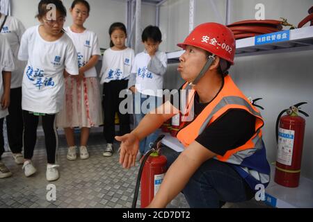 (200827) -- LANZHOU, Aug. 27, 2020 (Xinhua) -- A staff member of the China Construction Third Engineering Bureau Co., Ltd. introduces safety knowledge to children during a caring activity in Anning District of Lanzhou, northwest China's Gansu Province, Aug. 27, 2020. A caring activity for left-behind children in rural areas was held at a construction site of a women and children's hospital in Lanzhou on Thursday. Experts and volunteers conducted safety knowledge education to children and communicated with parents who are migrant workers here on family education and communication between paren Stock Photo