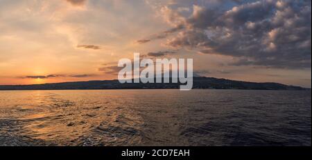 A stunning panoramic view of active Etna volcano and Catania at sunset, seen from the sea, Sicily Stock Photo