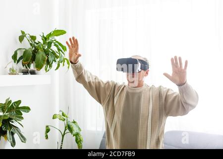Senior man wearing virtual reality goggles at home Stock Photo