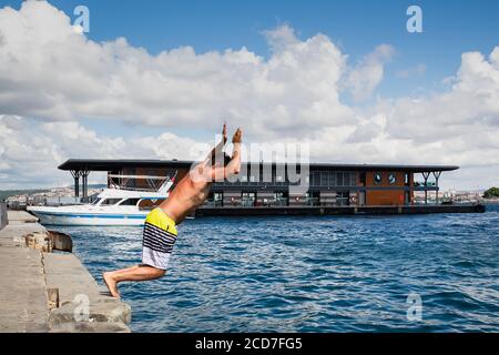 Young turkish man jumping in the sea from the pier of Karakoy on a hot summer day, the Golden Horn, Istanbul, Turkey.
