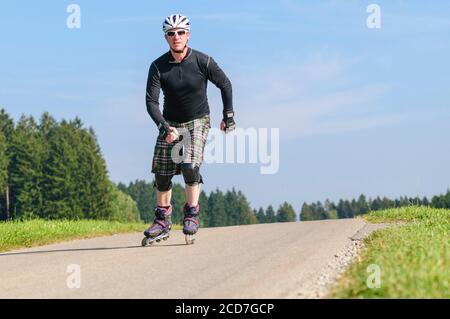 Man doing a tour on roller blades on a small way in countryside Stock Photo