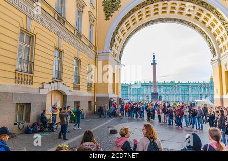 Saint Petersburg, Russia, August 4, 2019: street musicians are playing their instruments and people surrounded in Arch of General Staff Building in city centre, State Hermitage Museum background