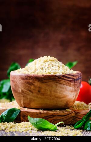 Raw barley bulgur in a wooden bowl, vintage background, selective focus Stock Photo