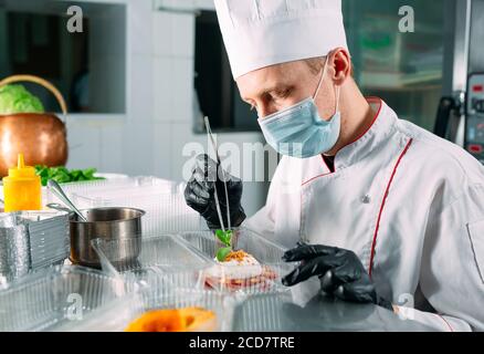 Food delivery in the restaurant. The chef prepares food in the restaurant and packs it in disposable dishes. Stock Photo