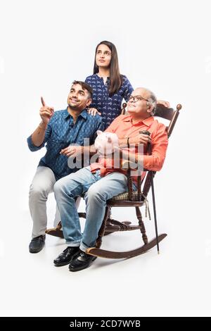 Indian father with daughter holding piggy bank while sitting on ...
