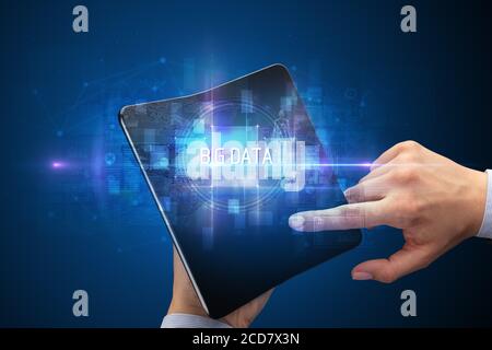 Businessman holding a foldable smartphone with BIG DATA inscription, new technology concept Stock Photo
