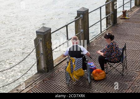 Woman with man in wheelchair on Bournemouth Pier fishing at Bournemouth, Dorset UK in August Stock Photo