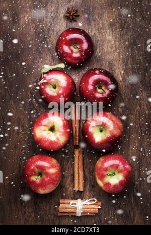 Creative Christmas tree made from red apples, cinnamon and anise star on wooden brown background Stock Photo