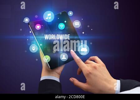 Businessman holding a foldable smartphone with WORLDWIDE inscription, social media concept